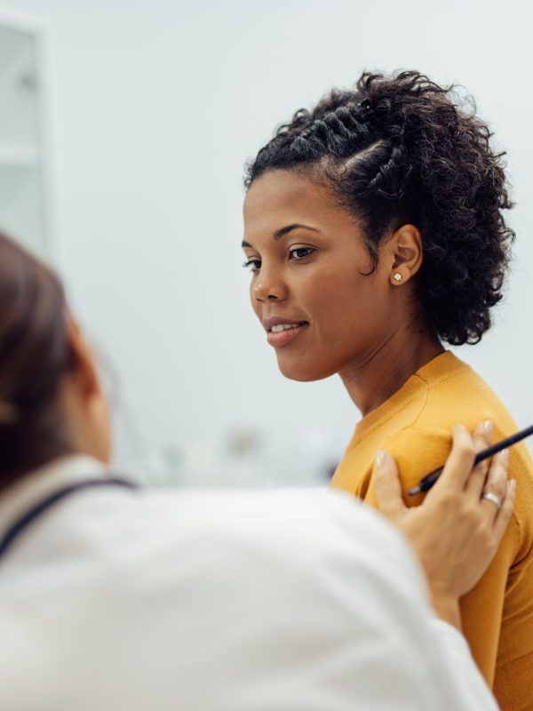 Caring doctor reassuring female patient at medical office.